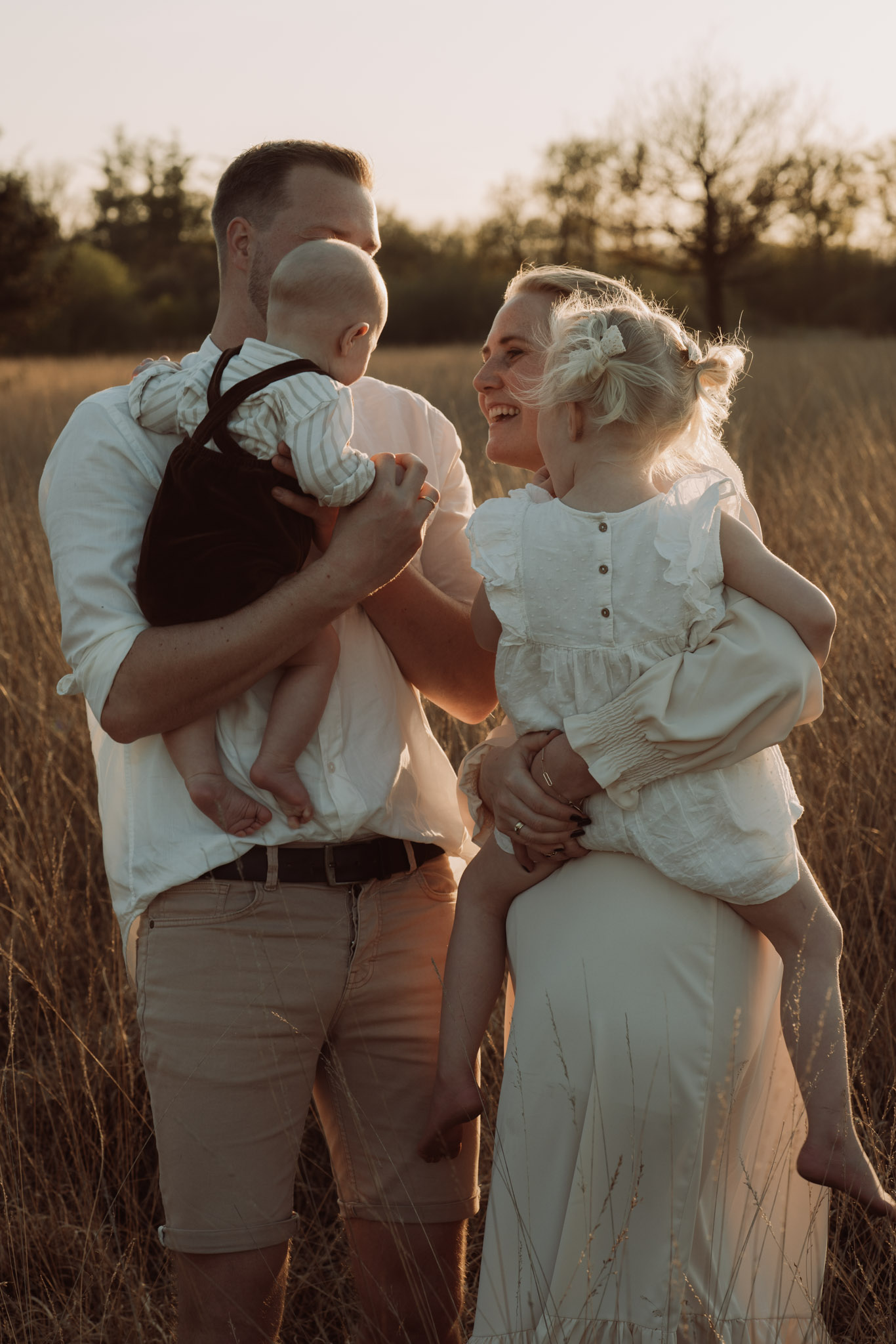 Gezinsfoto bij zonsondergang – twee kinderen en ouders in intiem moment tijdens golden hour