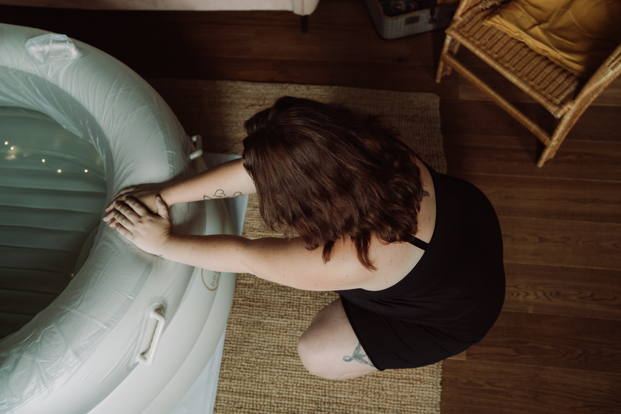 Geboortefotograaf Ede | Barende vrouw hurkend voor bevalbad