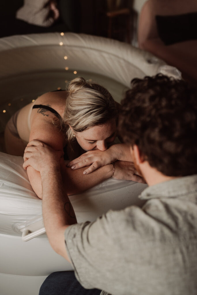 Vrouw in bevalbad gesteund door haar partner – intiem moment tijdens de bevalling