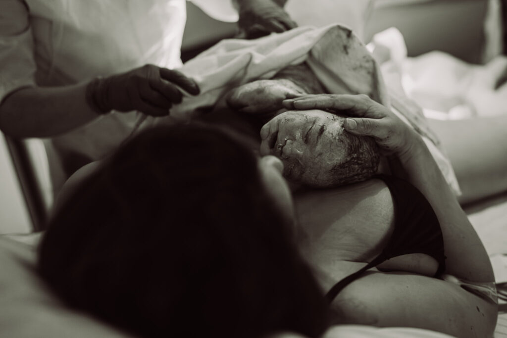 Geboortefotografie, moeder tijdens het eerste contact met haar zoontje 